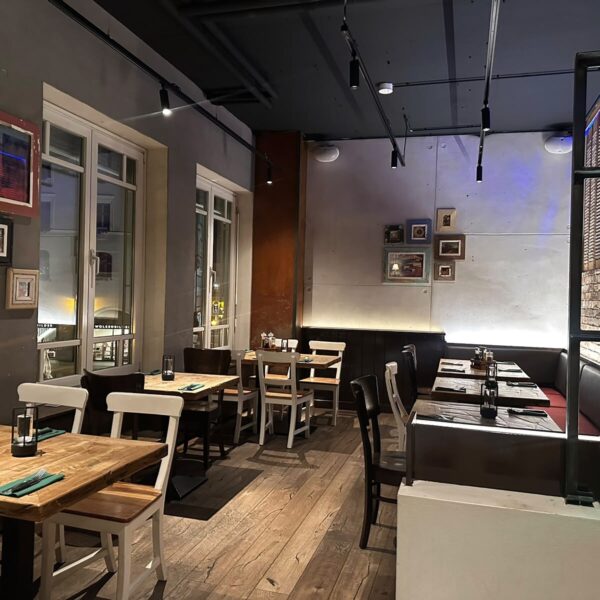 Speiseraum im Leo’s Augsburg mit Holztischen und großen Fenstern