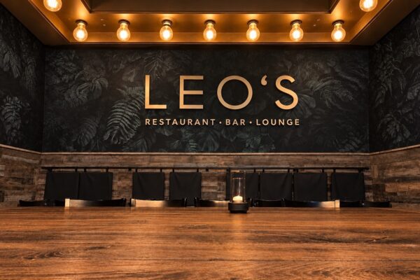 Gastraum im Leo’s Augsburg mit goldenem Schriftzug und Holztisch