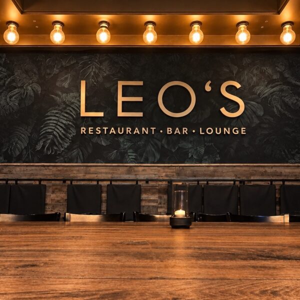 Gastraum im Leo’s Augsburg mit goldenem Schriftzug und Holztisch
